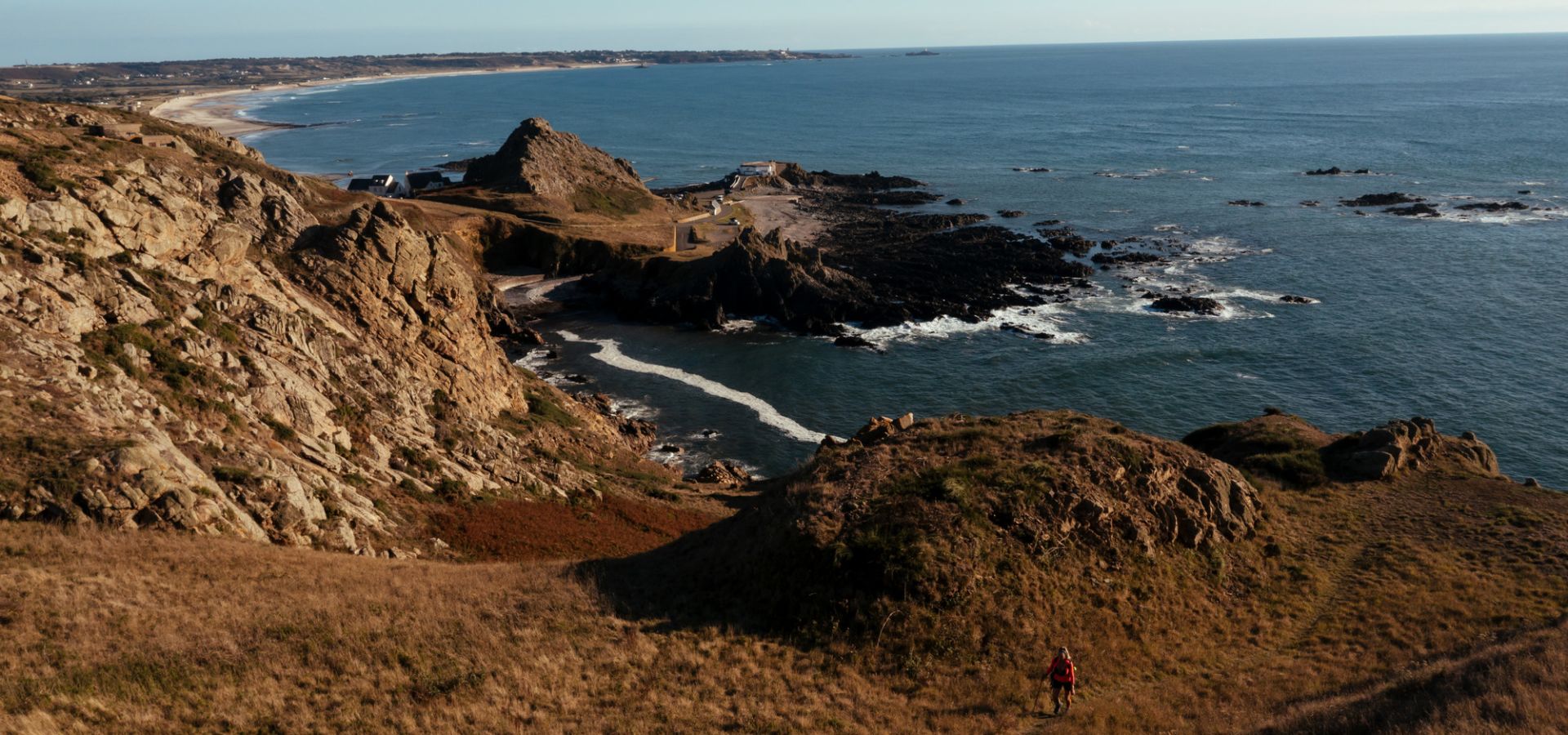A lady walking on the west coast of Jersey with the view of St. Ouen